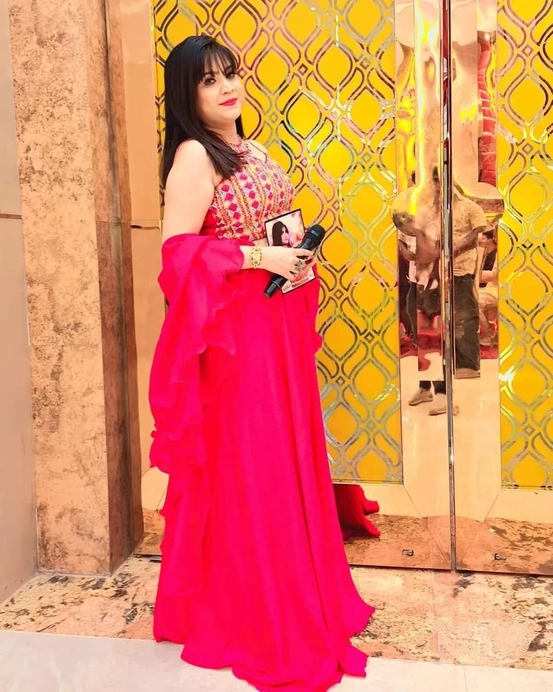 Female playback singer holding a microphone before a decorative golden venue entrance